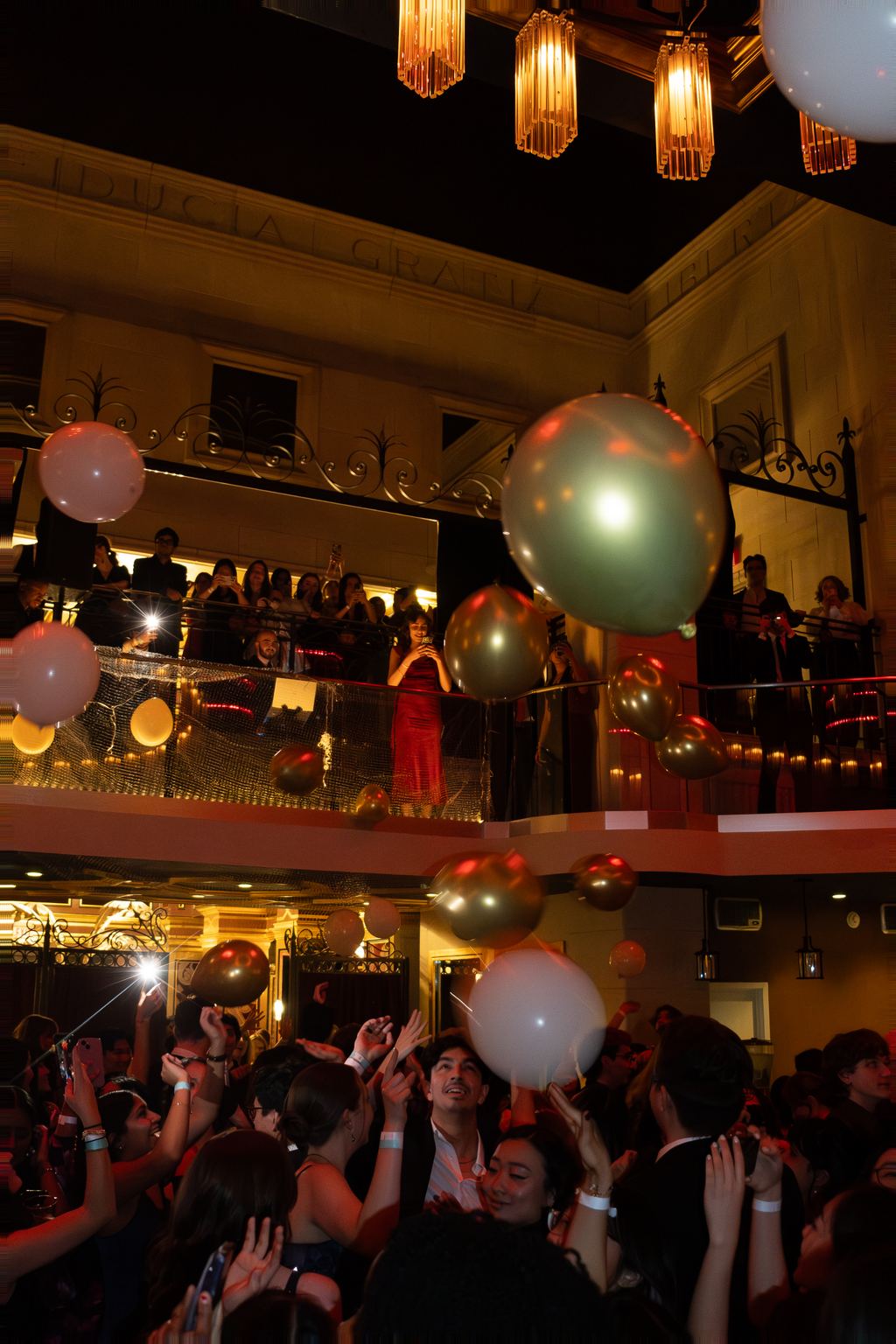 Balloon drop in a grand ornate ballroom with tiered balconies