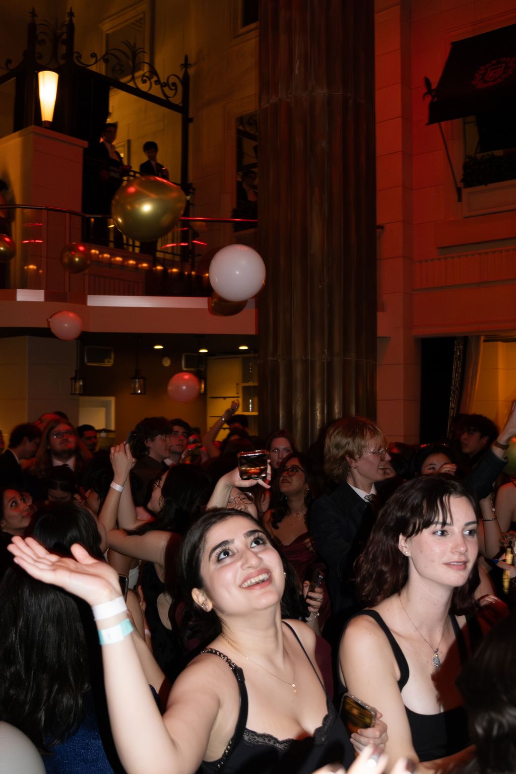 Guests reaching for falling balloons in a grand ornate ballroom