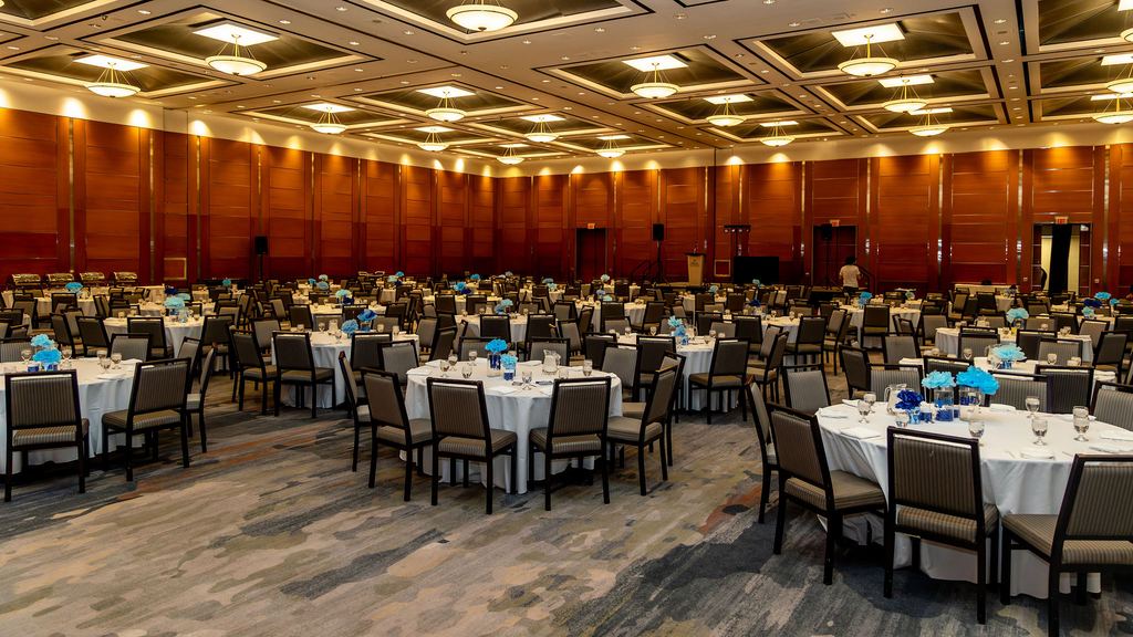 Ballroom set for a formal dinner with round tables and chandeliers