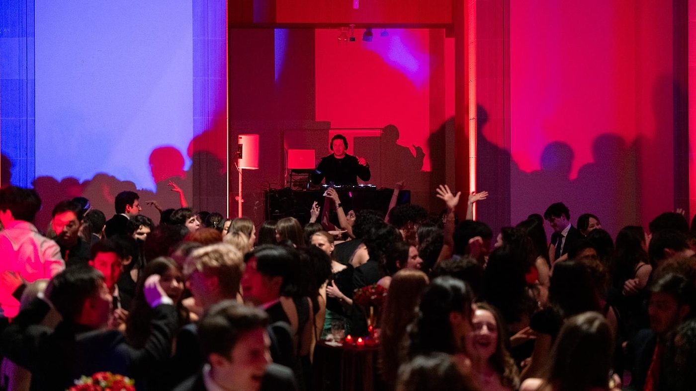 DJ performing for a packed dance floor under red and blue stage lighting