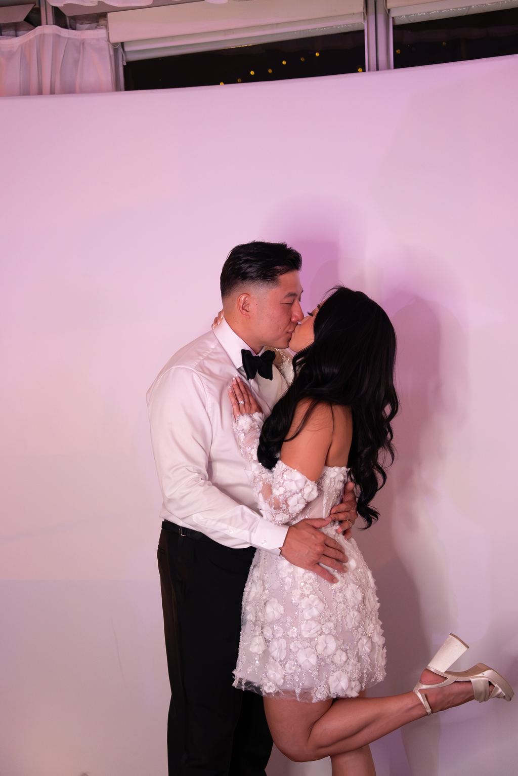 Bride and groom sharing a kiss lit in soft pink light